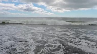Kunashir Adası 'nın sakin güzelliğini hissedin. Dalgalar yavaşça kumlu kıyıya çarpıyor. Huzurlu manzara bulutlu gökyüzünün altında denizin büyüleyici ritmini sergiliyor..