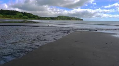 Kunashir Adası 'nın huzur dolu güzelliğini hissedin. Dalgalar yavaşça siyah kumsalda yuvarlanırken..