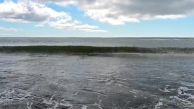 Experience the captivating movement of ocean waves rolling onto the sandy beaches of Kunashir Island.