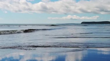 Kumlu sahilde dalgalar dans ederken Kunashir Adası 'nın sakin güzelliğini hissedin. Okyanus huzurlu bir gökyüzünü yansıtıyor, doğa aşıklarını bu kıyı cennetinde rahatlamaları ve rahatlamaları için davet ediyor..