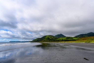 Dalgalar, Rusya 'nın sakin kıyı şeridinde yavaşça süzülürken bulutlar yukarı doğru sürükleniyor. Bereketli yeşil tepeler suyla buluşmak için çağlayarak sakin bir günde huzurlu ve resimsel bir manzara yaratıyor..