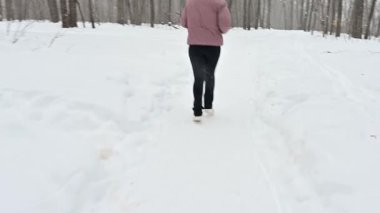 Sakin bir kış harikalar diyarında, fit silueti olan bir kız taze karda koşar. Huzurlu orman etrafını sarmış, uzun ağaçlar kar tanelerinin arasında sessizce duruyor..