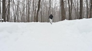 Bir adam kışın harikalar diyarında karla kaplı bir yolda hızla koşar. Taze havanın ve ormanın güzelliğinin tadını çıkarırken etrafında kar taneleri uçuşuyor. Atletik ruhu kar fırtınasında parlıyor..