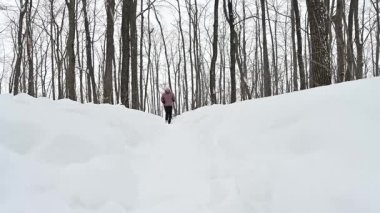 Kararlı bir kadın, temiz havayı ve huzurlu çevreyi kucaklayarak, karlı bir ormanda yokuş yukarı koşar. Yükselen ağaçlar ve saf beyaz karla çevrili her adımda sınırlarını zorluyor..