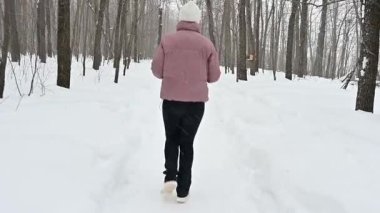 Taze karla kaplı sakin bir ormanda, kararlı bir sporcu kış manzarasında zarafetle koşar. Soğuğu kucaklar gibi etrafında hafif hafif hafif dans eder..