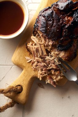 Barbekü soslu domuz eti ve ahşap kesim tahtasında otlar.