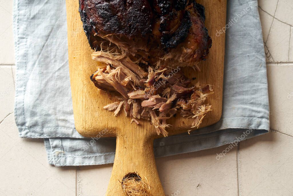 Closeup of glazed pulled pork on wooden cutting board with table towel
