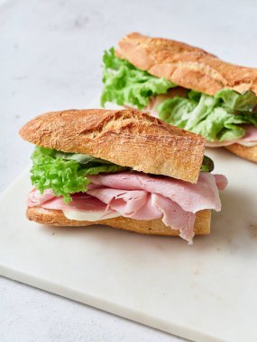 Baget, jambon, mozzarella peyniri ve maruldan yapılan taze dilimlenmiş sandviçler servis edilir.