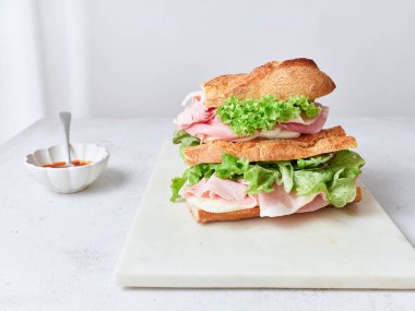 Sağlıklı bir sandviç baget, mozzarella peyniri, marul ve jambon kullanarak hazırlanır..