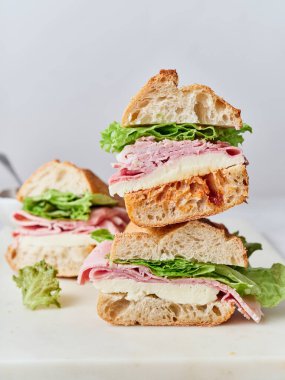 Öğle yemeğinde baget, jambon, mozzarella ve maruldan yapılmış bir yığın sandviç gösteriliyor..