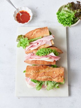 Birkaç sandviç baget, mozzarella peyniri, jambon, marul ve domates sosuyla yapılır.