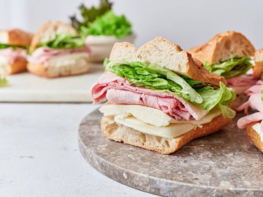 Bir masada jambon, mozzarella ve marulla dolu dilimlenmiş sandviçler sergilenir. Kahvaltı ya da öğle yemeği için yemek..