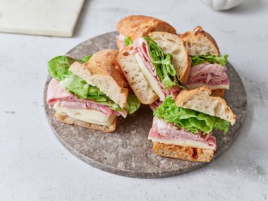 Sağlıklı bir sandviç mozzarella peyniri, marul ve jambonla hazırlanır..