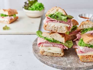 Yemek masasında jambon, mozzarella ve marul dolu sağlıklı sandviçler var..