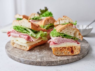 Masa, mozzarella peyniri, jambon ve marul dilimli sandviçlerle dolu..