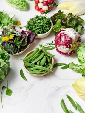 Taze marul ve sebzeler mermer tezgahta sergilenir. Bu düzenek turşu, romaine, romagula ve turp gibi sağlıklı bir yemek için gerekli malzemeleri gösteriyor..