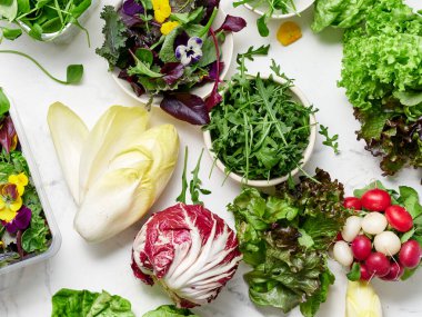 Taze marul ve sebzeler mermer tezgahta sergilenir. Farklı sebzeler salata yapmak için hazırdır. Parlak renkler vejetaryen bir yemek için sağlık ve lezzet gösterir.