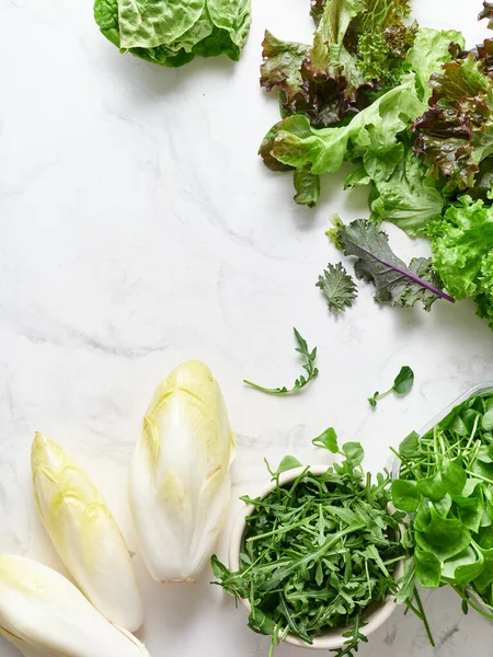 Bir mermer tezgahta çeşitli marul ve sebzeler düzenlenir. Bunlar radicchio, romaine, rogula ve chicory içerir..