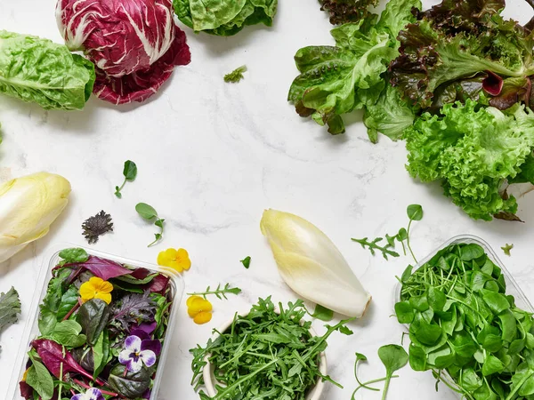 Mutfak tezgahında yemek hazırlığı için bir dizi marul ve sebze sergileniyor. Çeşitli yeşillikler ve turplar sağlıklı salata yapmak için bir arada otururlar..