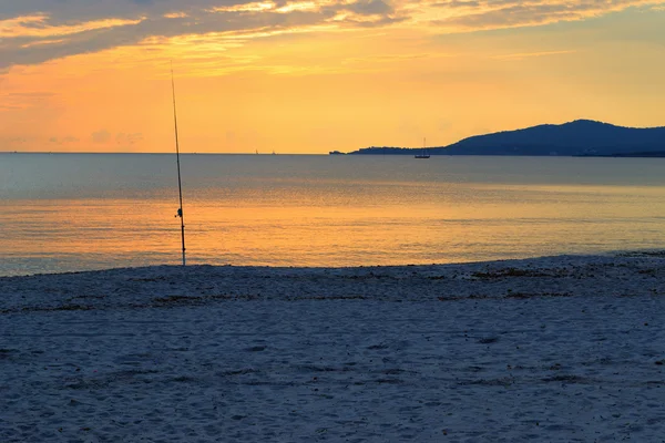 Vara de pesca na areia ao pôr do sol — Fotografia de Stock