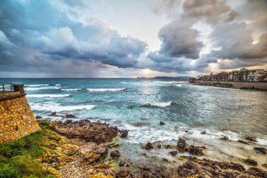 Alghero kıyı şeridi batımında dramatik gökyüzü altında