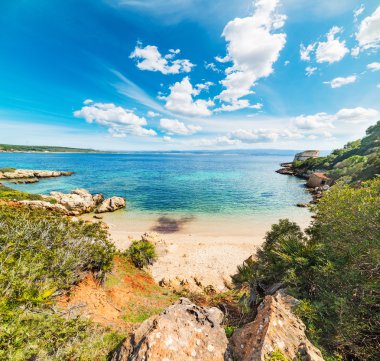 Beyaz bulutların üzerinde Alghero'da küçük bir koy