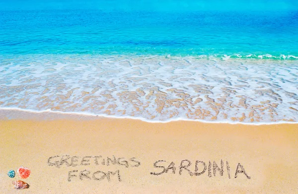 Saudações da sardenha escritas em uma praia tropical — Fotografia de Stock