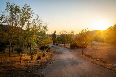 Gün batımında açık bir gökyüzünün altında köy yolu. Sardunya, İtalya