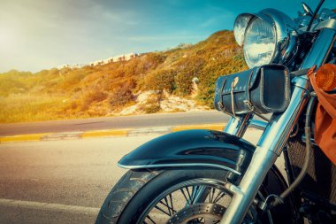 Gün batımında bir kır yolunun kenarına park edilmiş klasik bir motosiklet.