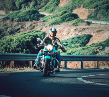 Şehir yolunda klasik bir motosiklet kullanan bir motorcunun ön görüntüsü.