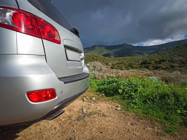 Kırsal kesimde dramatik bir gökyüzünün altında gri bir SUV görüldü. Sardunya, İtalya
