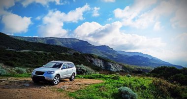 Modern gri SUV bulutlu bir gökyüzünün altında park halinde.