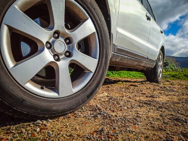 Kırsalda, mavi bir gökyüzünün altında, yerden görünen bulutlarla park edilmiş modern bir SUV 'a yakın durun.