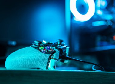 Karanlık bir odada arka planda pc rgb dosyası olan oyun denetleyici