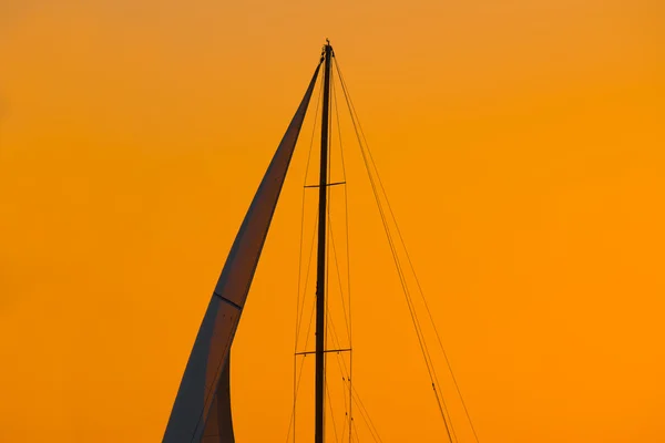 Nærbillede af en sejlsilhuet under en orange himmel ved solnedgang - Stock-foto