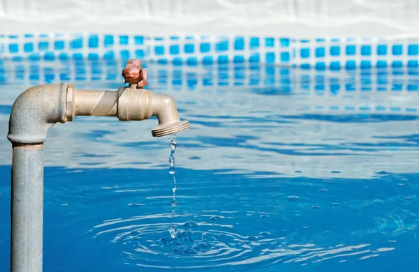 Rubinetto gocciolante in una piscina blu — Foto Stock