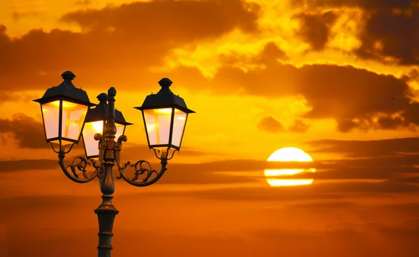 Orange sky with a shining sun and a lamppost — Stock Photo, Image