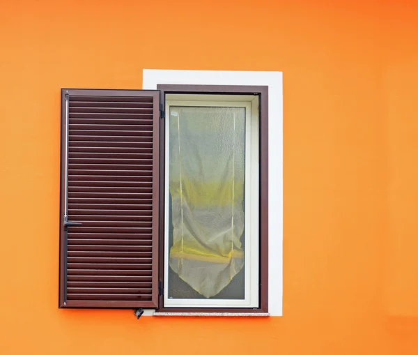 Καφέ παράθυρο σε έναν πορτοκαλή τοίχο — Φωτογραφία Αρχείου