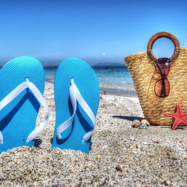 Sandales bleues et sac de paille près du rivage — Photo