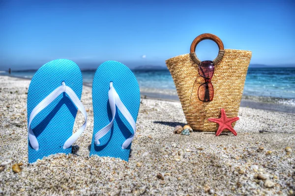 Sandales bleues et sac de paille près du rivage — Photo