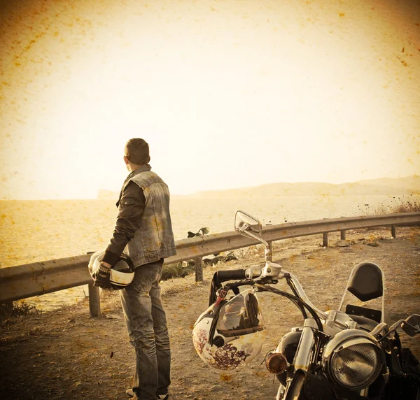 Motociclista y motocicleta junto al mar en tono vintage — Foto de Stock