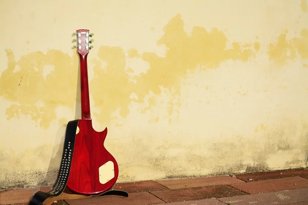 Електрична гітара нахилилася на сільську стіну — стокове фото