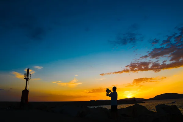 Turista e farol ao pôr do sol — Fotografia de Stock