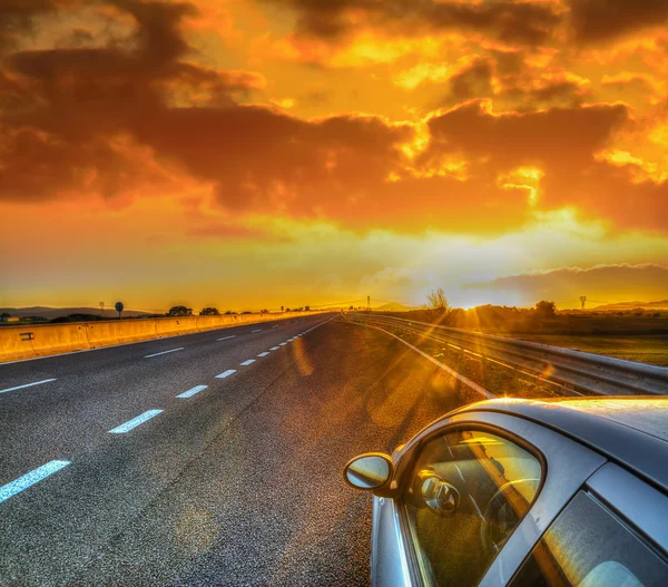 Car on the edge of the road under a scenic sky at sunset — Stock Photo, Image