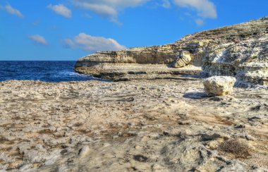 Sardinya bulutlar altında kayalık sahil