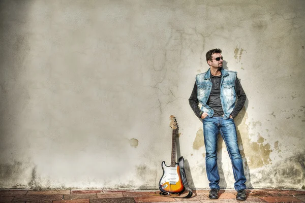 Mann und Gitarre lehnen an der Wand — Stockfoto