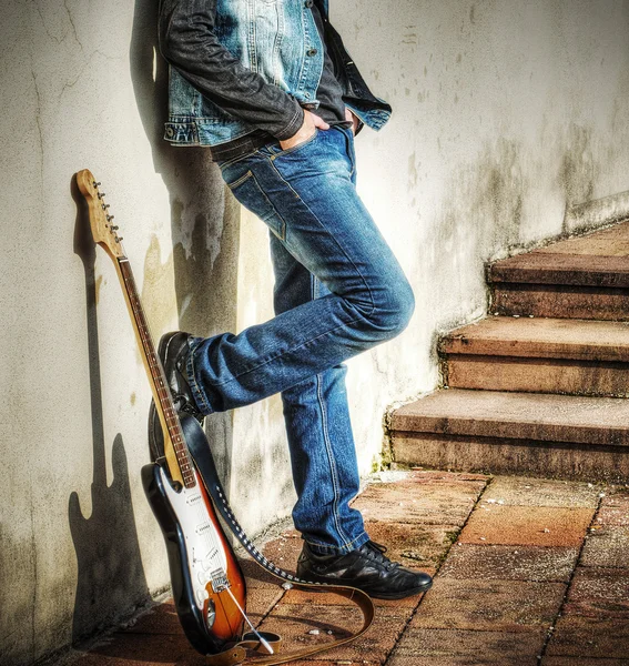 Guitarra e homem apoiado na parede — Fotografia de Stock