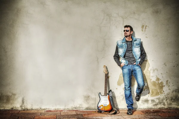 Mann und Gitarre gegen grungy Wand in hdr — Stockfoto