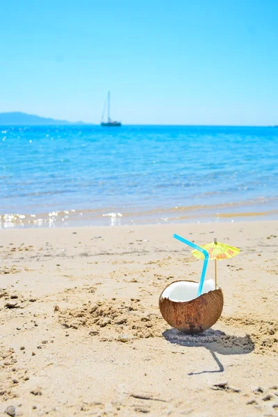 Kokos met stro en paraplu door de zee — Stockfoto