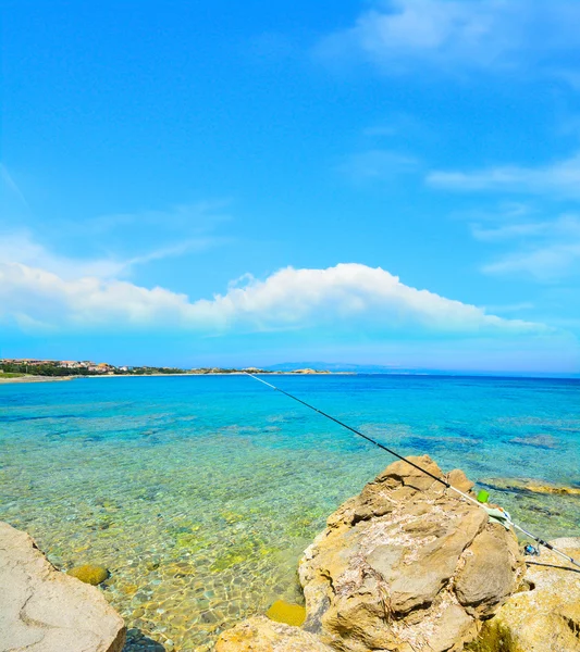 Fishing rod on yellow rocks in Capo Testa — Stock Photo, Image